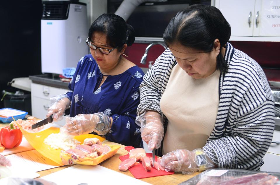 Elvie Hafner, left, and Meralyn Zigler cut chicken into small pieces for a chicken parmesan dish they parepared Friday, Feb. 9, 2024, during a Youth and Parent Cooking Class at Family Matters Resource Center in Alliance.