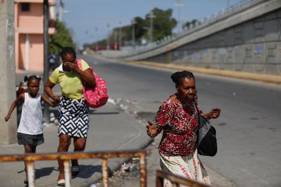 Pedestrians run during clashes between police and gangs in Port-au-Prince, Haiti, Wednesday, March 6, 2024. (AP Photo/Odelyn Joseph)