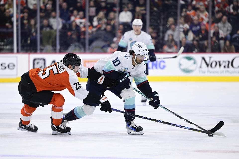 Seattle Kraken's Matty Beniers (10) skates the puck past Philadelphia Flyers' Ryan Poehling (25) during the first period of an NHL hockey game, Saturday, Feb. 10, 2024, in Philadelphia. (AP Photo/Derik Hamilton)