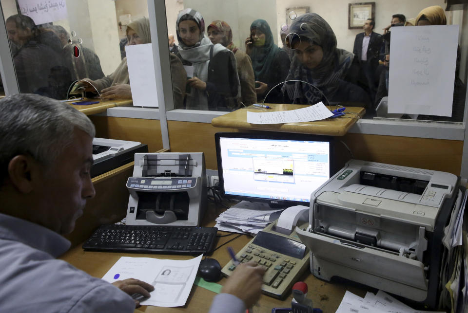 Palestinian Hamas government employees queue to receive 50 percent of their long-overdue salaries donated by Qatar, at the main Gaza Post Office, in Gaza City, Friday, Dec. 7, 2018. Gaza's Hamas rulers received dollars 15 million from Qatar to help pay the salaries of the territory's civil servants. (AP Photo/Adel Hana)