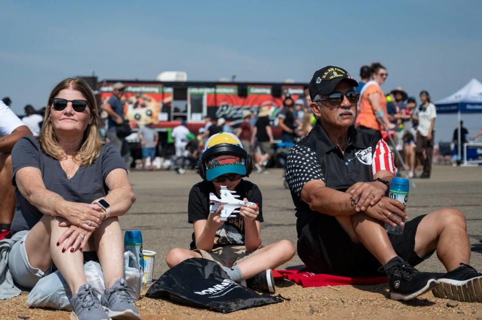 Camden Carrick, 9, plays with a toy F-16 while his grandparents Sharon and Tommie Taberna watch the Beechcraft F33C Bonanza perform tricks at the California Capital Airshow on Sunday at Mather Airport.