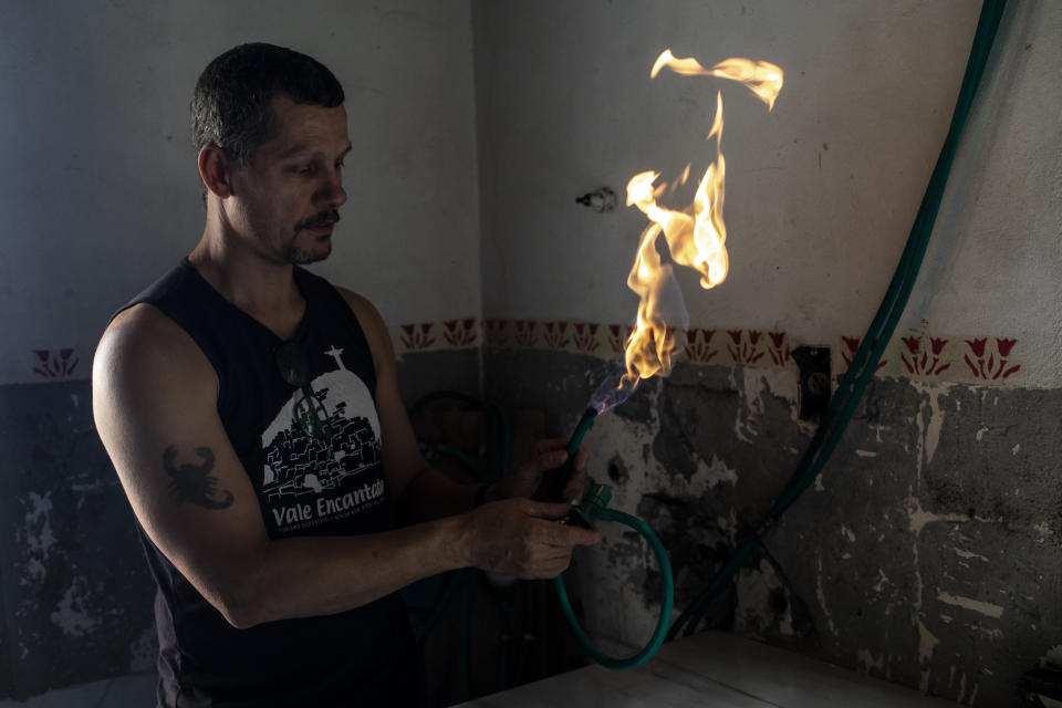 Residents' association President Otavio Alves Barros handles a line with gas generated by the sewage treatment biosystem in the Enchanted Valley sustainable community on the outskirts of Tijuca National Forest in Rio de Janeiro, Brazil, Monday, June 6, 2022. Electricity arrived in the late 20th century to the low-income Enchanted Valley community, but the utility never connected it to the city’s sewage network, so its residents set out to solve the problem on its own by building a biodigester and artificial wetland to process all sewage generated by all of its 40 families. (AP Photo/Bruna Prado)