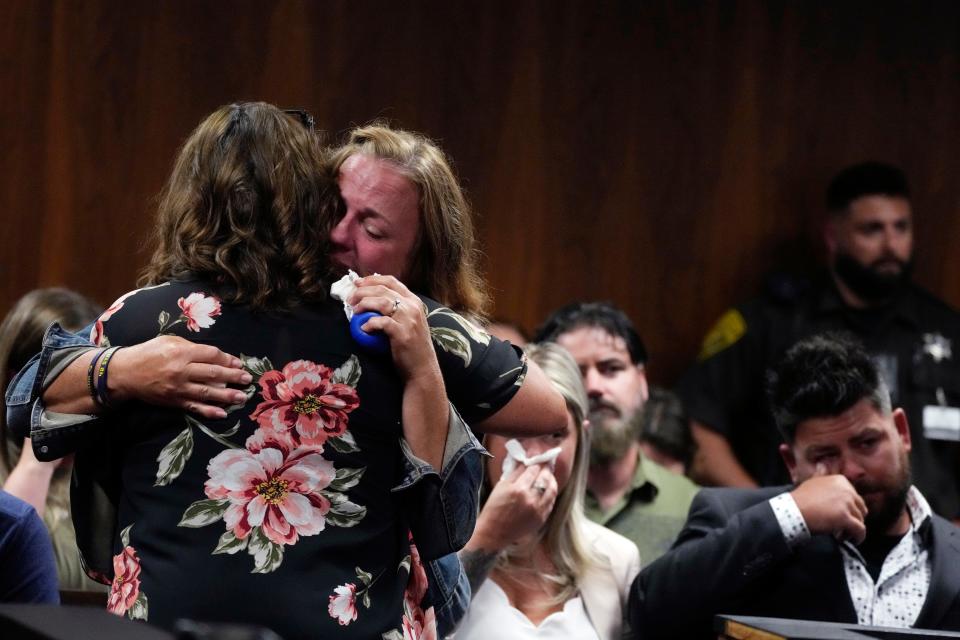 Sheri Myre, background, mother of slain Oxford student Tate Myre, hugs assistant principal Kristy Gibson-Marshall in court, on Friday, July 28, 2023, in Pontiac, Mich. Prosecutors are making their case that the Michigan teenager should be sentenced to life in prison for killing four students at his high school in 2021. Prosecutors introduced dark journal entries written by Ethan Crumbley, plus chilling video and testimony from a wounded staff member.