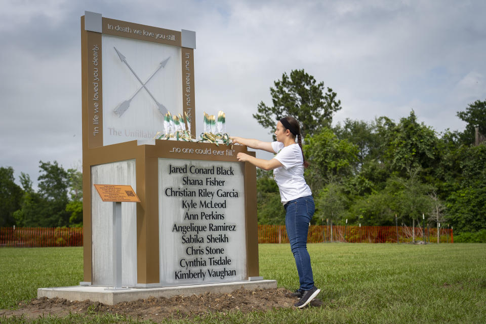 Morgan Wilson, who will graduate from Santa Fe High School this month, adjusts the ten feathers representing the ten victims of the 2018 Santa Fe school shooting where they sit on a new memorial, Tuesday, May 18, 2021, outside of the high school in Santa Fe, Texas. The Santa Fe Ten Memorial Foundation unveiled the "Unfillable Chair," a student designed memorial, on the third anniversary of the shooting. The foundation is planning a larger memorial for the future. (Mark Mulligan/Houston Chronicle via AP)