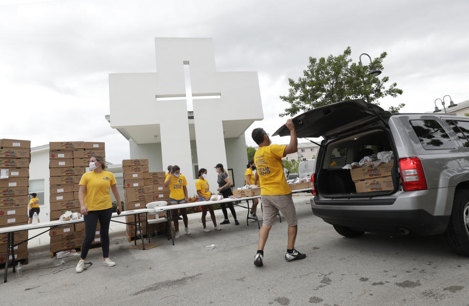 Volunteers load groceries into cars during a food distribution event, Tuesday, July 21, 2020, at St. Monica's Catholic Church in Miami Gardens, Fla. (AP Photo/Wilfredo Lee)