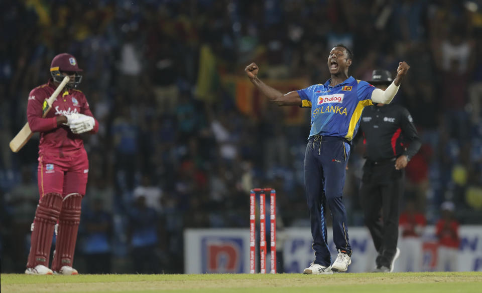 Sri Lanka's Angelo Mathews, right, celebrates the his team's victory over West Indies' by six runs as Sheldon Cottrell looks on during the third one day international cricket match between Sri Lanka and West Indies in Pallekele, Sri Lanka, Sunday, March 1, 2020. (AP Photo/Eranga Jayawardena)