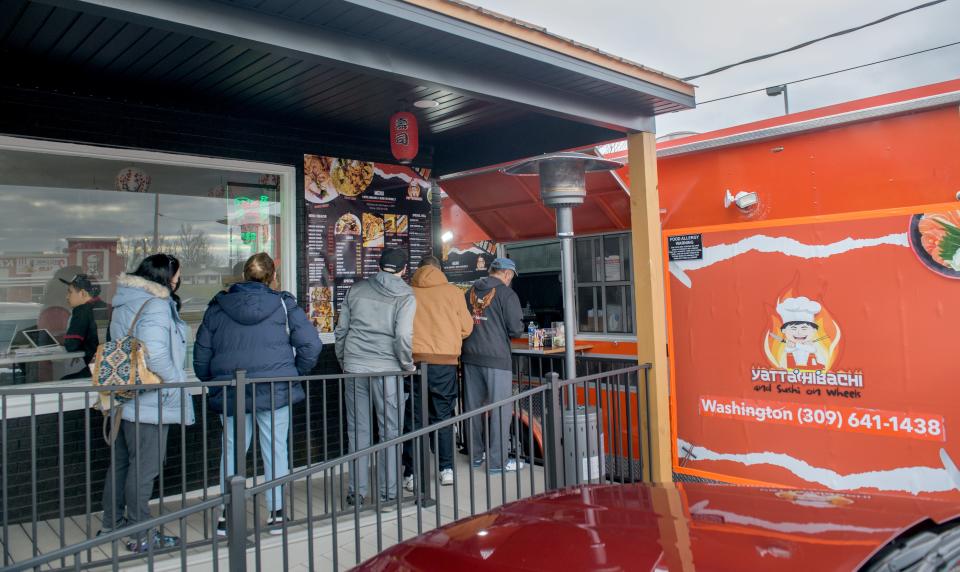 Customers line up to check out the menu and order at the window of the mobile food truck at the new Yatta Hibachi & Sushi restaurant Thursday, Jan. 4, 2024 at 1107 Peoria Street in Washington. Customers can wait for their order and enjoy their food in the dining room in the building next to the truck.