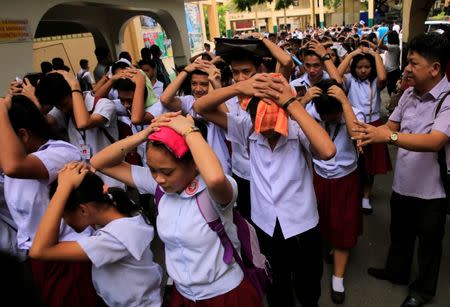 Students use their hands to cover their heads as they evacuate their school premises after an earthquake of magnitude 6.2 hit the northern island of Luzon and was felt in the Metro Manila, Philippines August 11, 2017, shaking buildings and forcing the evacuation of offices and schools. REUTERS/Romeo Ranoco