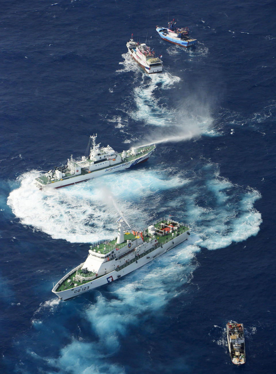 A Japan Coast Guard's patrol boat, third from the top, and a Taiwanese patrol boat, 4th from the top, discharge water each other near disputed islands called Senkaku in Japan and Diaoyu in China, in the East China Sea, Tuesday, Sept. 25, 2012. On Tuesday morning, about 50 Taiwanese fishing boats accompanied by 10 Taiwanese surveillance ships came within almost 20 kilometers (about 12 miles) of the disputed islands - within what Japan considers to be its territorial waters, said Yasuhiko Oku, an official with the Japanese coast guard. (AP Photo/Kyodo News)