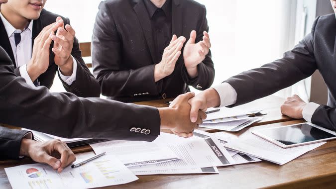 a group of people sitting at a table shaking hands