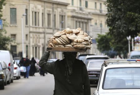 A man carries freshly baked bread on his head along a street in Cairo, Egypt, February 8, 2016. Picture taken February 8, 2016. REUTERS/Asmaa Waguih