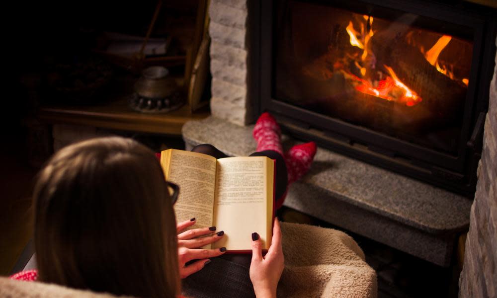 Woman reading book by fire