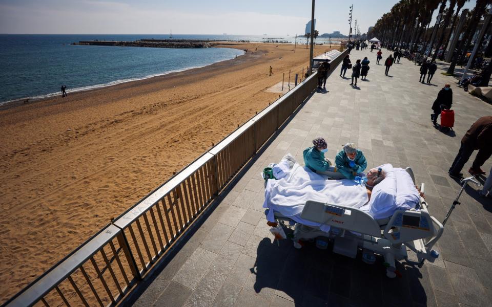 COVID-19 patient, Joan Soler Sendra, 63, who is deaf-mute, reads the lips and gestures of doctor Andrea Castellvi as he watches the sea as part of a "sea therapy", 114 days after he was admitted to Hospital del Mar, in Barcelona - NACHO DOCE/REUTERS