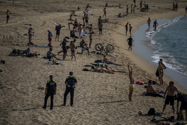 Police officers stand at the beach as they ask people to not sit, in Barcelona, Spain (Emilio Morenatti/AP)