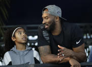 FILE - In this July 26, 2018, file photo, former Los Angeles Laker Kobe Bryant and his daughter Gianna watch the U.S. national championships swimming meet in Irvine, Calif. Federal safety officials are expected to vote Tuesday, Feb. 9, 2021, on what likely caused the helicopter carrying Kobe Bryant, his 13-year-old daughter and seven others to crash into a Southern California hillside last year, killing all aboard. (AP Photo/Chris Carlson, file)