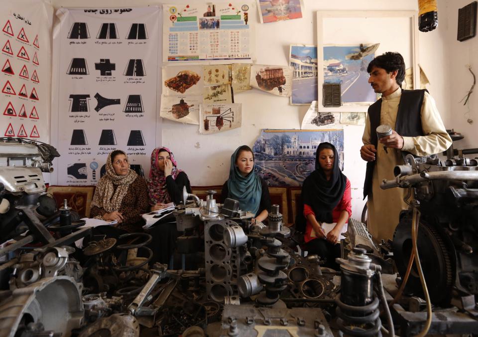 An instructor teaches women about a car's mechanics during a technical lesson at a driving school in Kabul