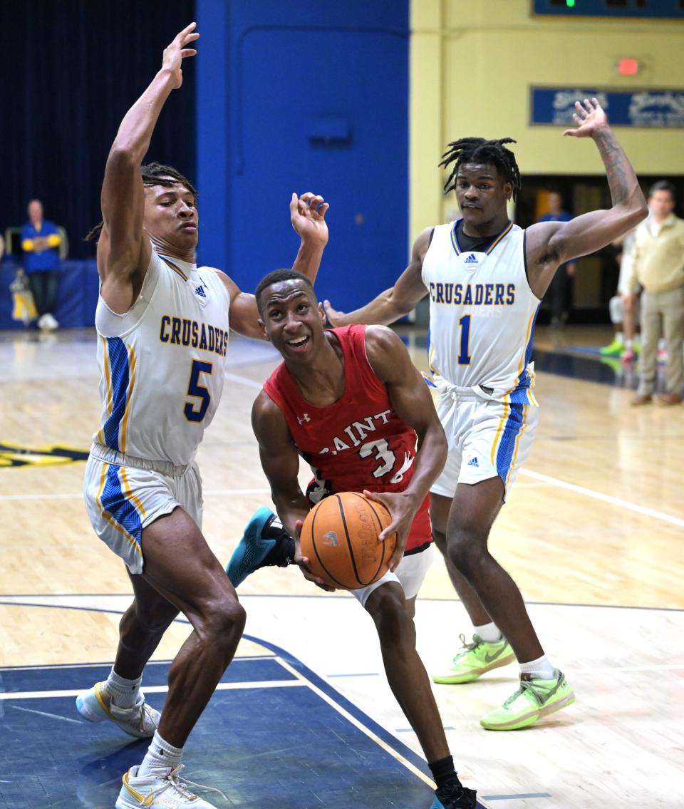 Cardinal Newman's Max Redmon (5) and Jermaine Council (1) cover up a Saint Andrews player while defending the basket during a game on Jan. 30, 2024.