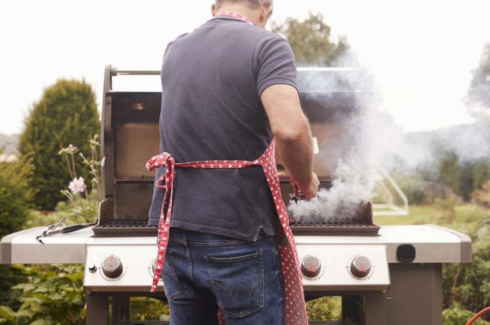 A man grills outdoors wearing a polka-dot apron in his backyard. The article is related to Sex & Love