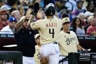 Arizona Diamondbacks' Ketel Marte (4) celebrates his run scored against the Los Angeles Dodgers with Diamondbacks' David Peralta, left, and Diamondbacks manager Torey Lovullo, right, during the fifth inning of a baseball game Saturday, Sept. 25, 2021, in Phoenix. (AP Photo/Ross D. Franklin)