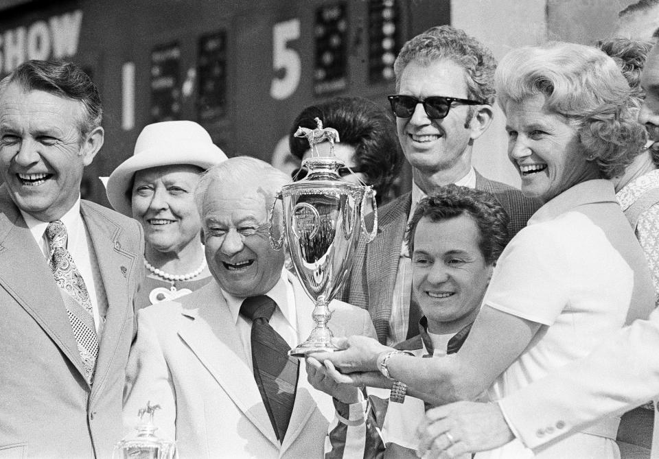 FILE - Penny Chenery, owner of Secretariat, right, jockey Ron Turcotte, second from right, and trainer Lucien Lauren, third from left, show off trophy in the Winner's Circle at Churchill Downs in Louisville, Kentucky, May 5, 1973, after Turcotte rode Secretariat to a record win in the 99th Kentucky Derby. (AP Photo/File)