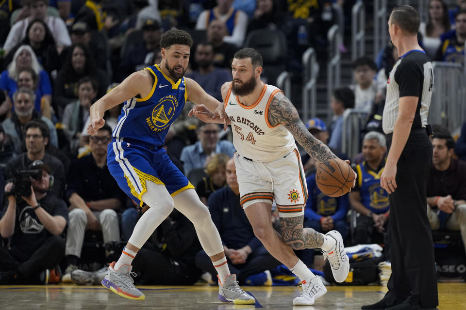 San Antonio Spurs forward Sandro Mamukelashvili, right, moves the ball while defended by Golden State Warriors guard Klay Thompson during the first half of an NBA basketball game Saturday, March 9, 2024, in San Francisco. (AP Photo/Godofredo A. Vásquez)