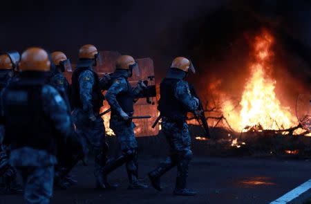 Riot police prepare to clash with members of Brazil's Homeless Workers Movement (MTST) near a burning barricade on BR-290 highway during a protest against President Michel Temer's proposal to reform Brazil's social security system, during the general strike in Eldorado do Sul, Rio Grande do Sul state, Brazil June 30, 2017. REUTERS/Diego Vara