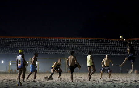 Residents play beach volleyball during at night on Copacabana beach, where the Olympic beach volleyball will take place in Rio de Janeiro, Brazil, July 9, 2015. REUTERS/Sergio Moraes