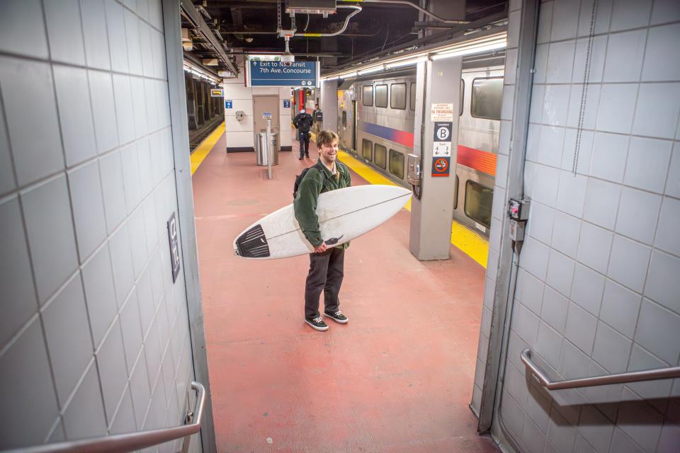 The author standing in a subway station, with his board under his arm.