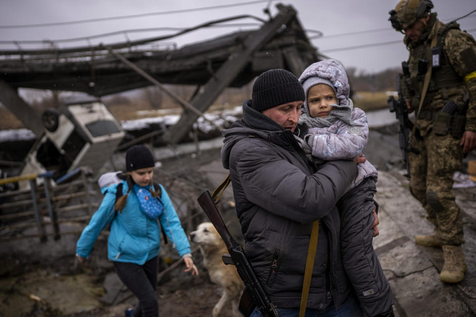 A Ukrainian militiaman helps a child across a bridge 