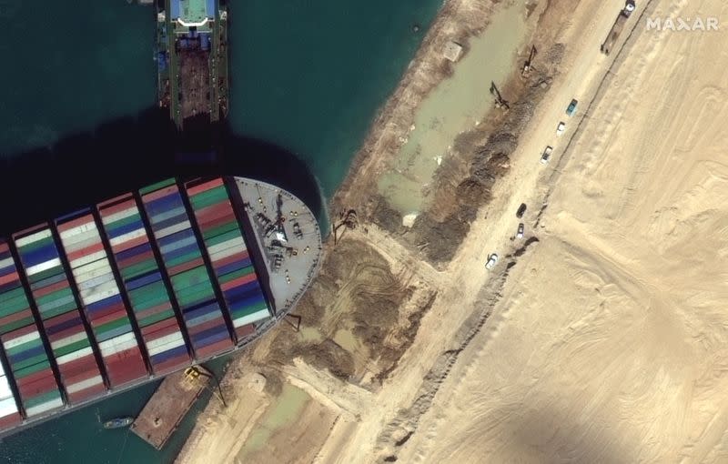 A view of the earth moving equipment excavating sand near the bow of the Ever Given container ship, in Suez Canal