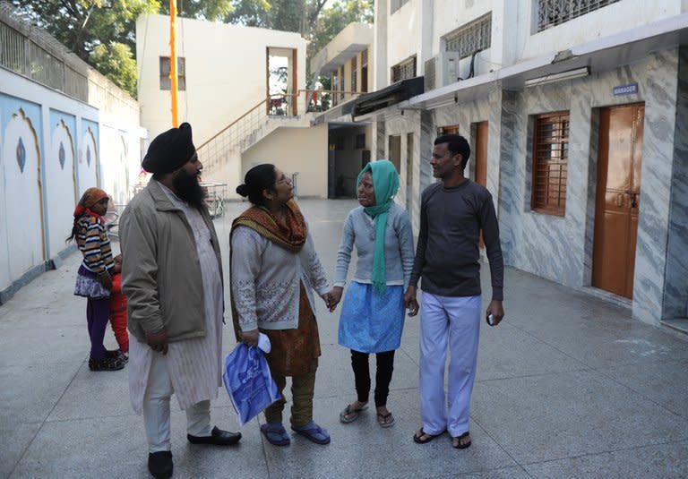 Acid attack survivor Sonali Mukherjee (2nd R) speaks with neighbours as she and her father Chandi Das Mukherjee (R) visit a Sikh Temple in New Delhi, on December 6, 2012. When Sonali rejected the advances of three of her fellow students, they responded by melting her face with acid