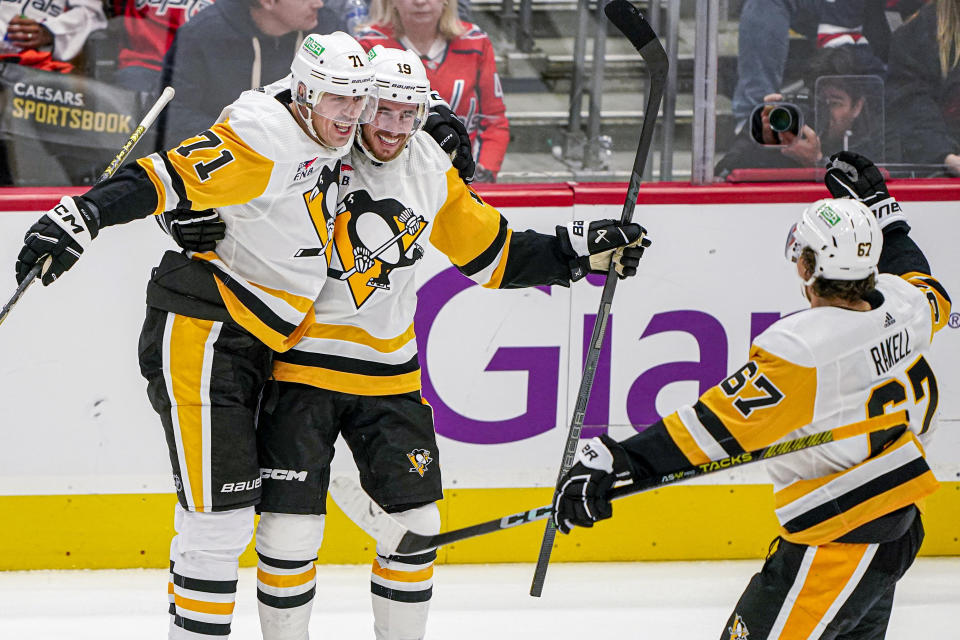 Pittsburgh Penguins right wing Reilly Smith (19) celebrates with center Evgeni Malkin (71) and right wing Rickard Rakell (67) after his goal against the Washington Capitals during the third period of an NHL hockey game Friday, Oct. 13, 2023, in Washington. The Penguins won 4-0. (AP Photo/Andrew Harnik)