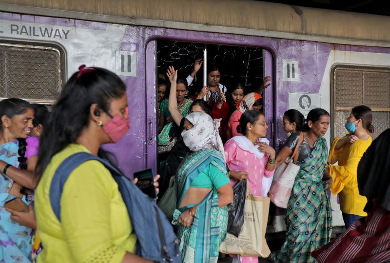 Women disembark from a suburban train at a railway station in Mumbai