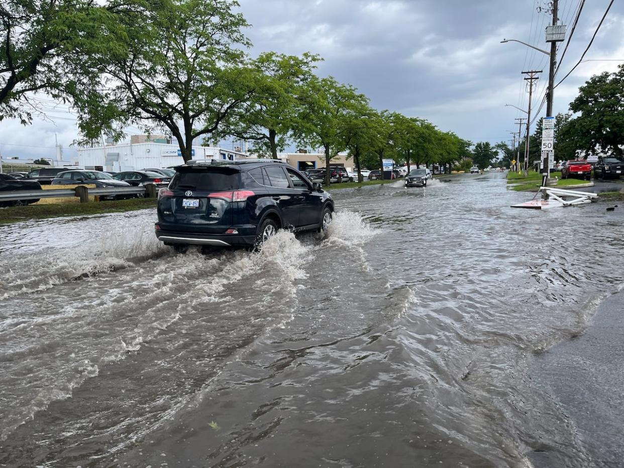 A vehicle makes its way down a waterlogged Ottawa street after a severe storm last July. Adding more permeable surfaces capable of absorbing stormwater could help the city become more resistant to such weather events. (Kristy Nease/CBC - image credit)