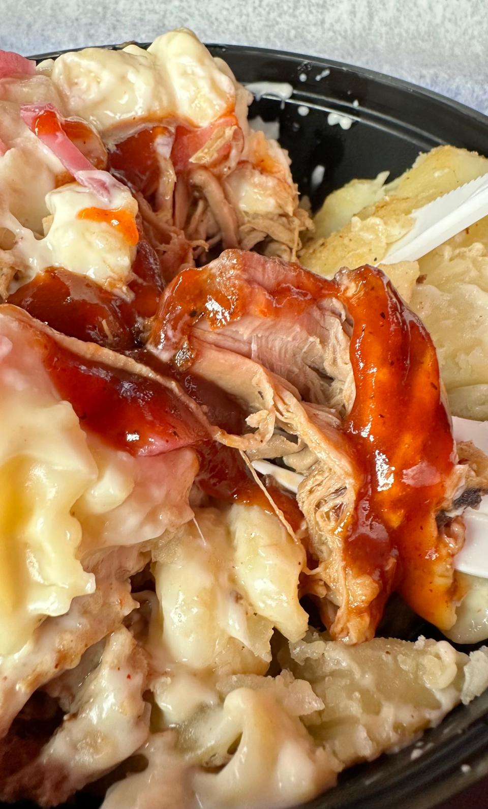 Slow-roasted, tender pulled pork combine with sides of extra white cheddar mac & cheese and Memphis sauce in a bowl served up at The Blazing Pig in Jackson Township.
