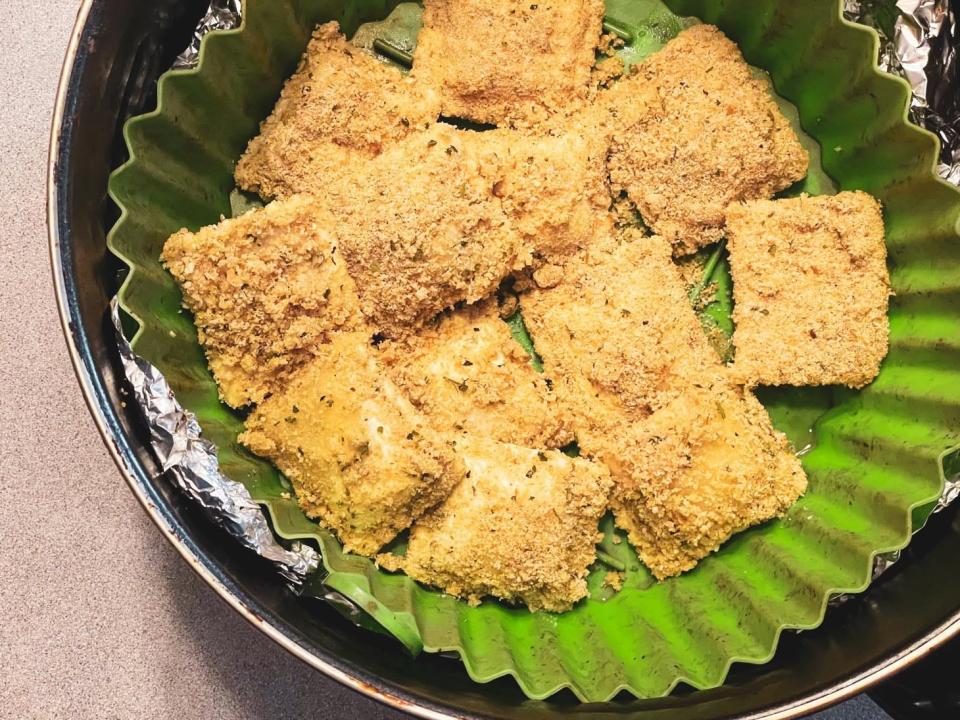 breaded ravioli in a silicone lining in an air fryer basket