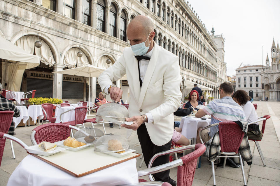 A waiter works in St. Mark's Square in Venice, northern Italy, Saturday, May 1, 2021. Italy is gradually reopening after six months of rotating virus closures allowing outdoor dining. (Filippo Ciappi/LaPresse via AP)