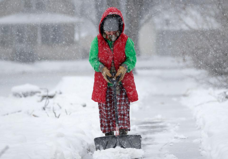 Kelly-Jo St. Aubin clears snow from the sidewalk at her home during a snowstorm Tuesday in Kaukauna.