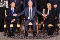 Israel's President Reuven Rivlin between Prime Minister Naftali Bennett and Foreign Minister Yair Lapid as they pose for a group photo with ministers of the new Israeli government