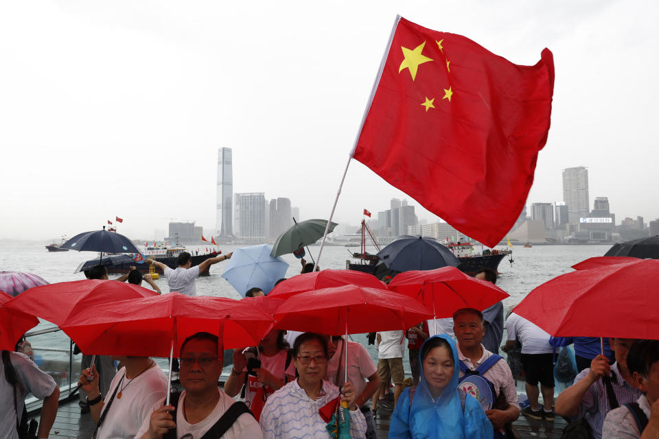 Pro-China supporters hold red umbrellas and a Chinese national flag during a counter-rally in support of the police in Hong Kong Saturday, July 20, 2019. Police in Hong Kong have raided a homemade-explosives manufacturing lab ahead of another weekend of protests in the semi-autonomous Chinese territory.(AP Photo/Vincent Yu)