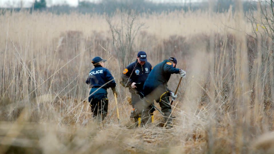 Crime scene investigators use metal detectors to search a marsh for the remains of Shannan Gilbert on December 12, 2011, in Oak Beach, New York. - James Carbone/Pool/Newsday/AP/File