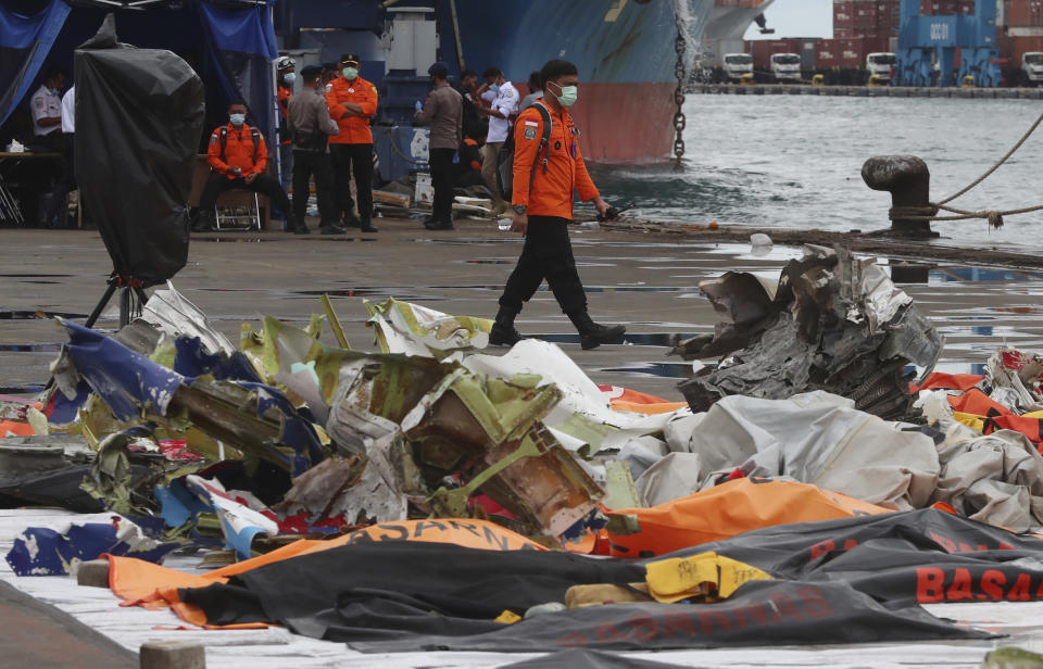 An Indonesian rescue team member walks near debris found in the waters around the location where a Sriwijaya Air passenger jet crashed, at the search and rescue command center at Tanjung Priok Port in Jakarta, Indonesia, Indonesia, Wednesday, Jan. 13, 2021. Divers looking for the crashed plane's cockpit voice recorder were searching in mud and plane debris on the seabed between Indonesian islands Wednesday to retrieve information key to learning why the Sriwijaya Air jet nosedived into the water over the weekend. (AP Photo/Achmad Ibrahim)