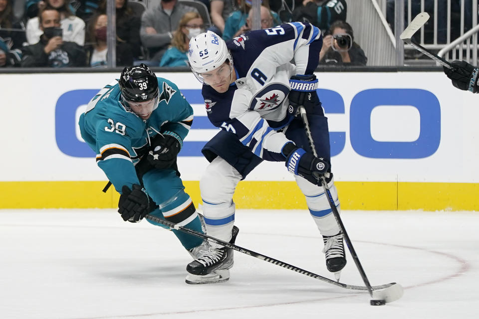 San Jose Sharks center Logan Couture, left, reaches for the puck next to Winnipeg Jets center Mark Scheifele during the first period of an NHL hockey game in San Jose, Calif., Saturday, Oct. 16, 2021. (AP Photo/Jeff Chiu)