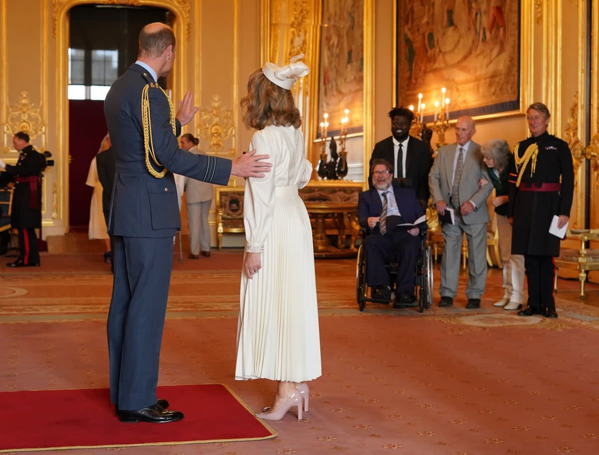 Kate Garraway, from London, is watched by her husband Derek Draper as she is made a Member of the Order of the British Empire by the Prince of Wales at Windsor Castl (PA)