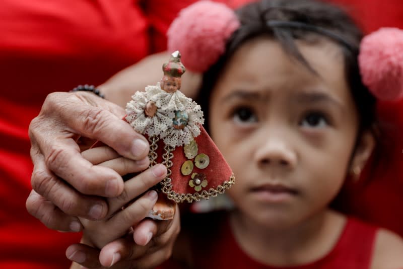 A girl holds a small replica of Baby Jesus during Catholic mass to celebrate its feast day in an evacuation center