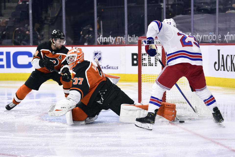 Philadelphia Flyers goaltender Brian Elliott makes a pad save on a shot from New York Rangers' Adam Fox, right, during the second period of an NHL hockey game, Saturday, March 27, 2021, in Philadelphia. (AP Photo/Derik Hamilton)