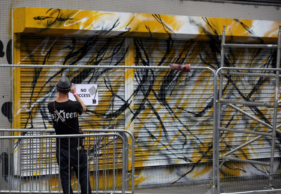 BRISTOL, ENGLAND - AUGUST 17: A man stops to take a photograph of part of the 'See No Evil' street art project at Nelson Street on August 17, 2012 in Bristol, England. The project, now in its second year, is Europe's biggest street art festival and has attracted top graffiti artists from all over the world. Organizers hope it will continue to be a draw for tourists visiting Bristol, often seen the spiritual home of underground artist Banksy. (Photo by Matt Cardy/Getty Images)