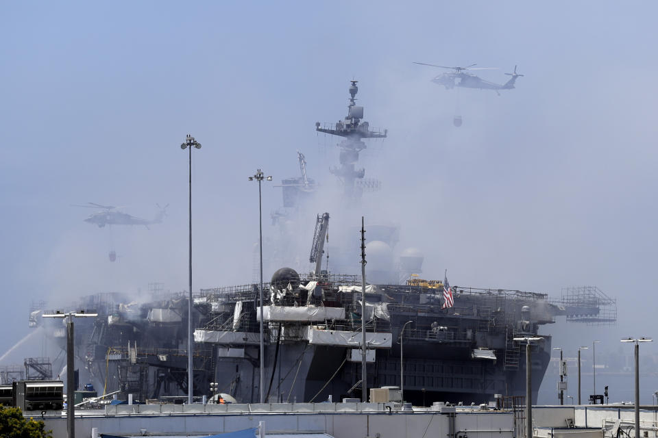 FILE - In this July 13, 2020, file photo, helicopters approach the USS Bonhomme Richard as crews fight the fire in San Diego. A sailor charged with starting the fire that destroyed USS Bonhomme Richard had been assigned to the ship's crew after dropping out of Navy SEAL training, according to a newly unsealed court document. The details about 20-year-old Ryan Mays and the investigation into the worst U.S. warship fire in recent memory were revealed in a search warrant unsealed Tuesday, Aug. 3, 2021, in U.S. District Court in San Diego. (AP Photo/Gregory Bull, File)