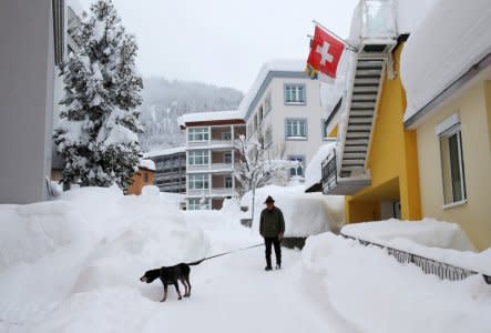 A man walks his dog after a snowfall ahead of the World Economic Forum (WEF) annual meeting in the Swiss Alps resort of Davos, Switzerland January 22, 2018  REUTERS/Denis Balibouse
