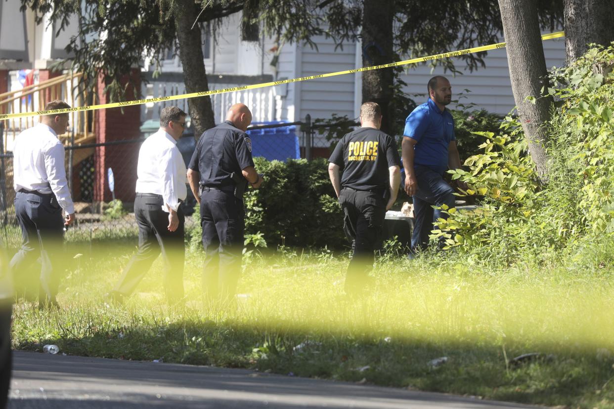 Rochester police investigate behind a house on the corner of Bauman and Laser Streets where two police officers were shot last night in this area in Rochester, N.Y., on Friday. 